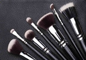 Set of professional makeup brushes over black leather background