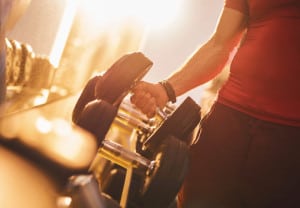 Unrecognizable man taking dumbbell from a rack.