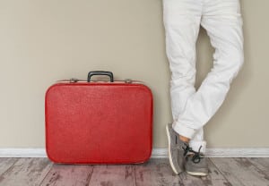 Man stands beside suitcase, home interior