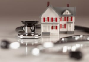 Stethoscope and Model House on Gradated Background with Selective Focus.