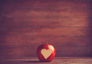 Apple with a heart cut into it. Photo in old color image style.