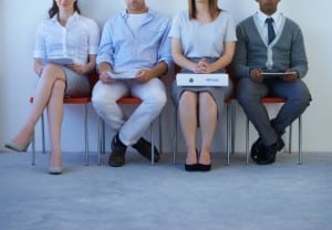 A young woman with a large resume sitting with other prospective employees
